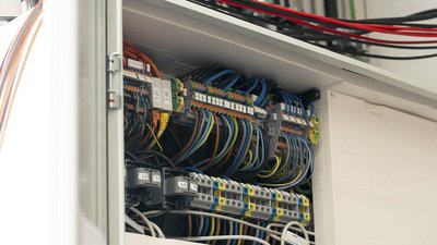 Der Innenraum eines Schaltschranks zeigt eine Vielzahl von Kabeln und elektrischen Komponenten, die sorgfältig verbunden sind.