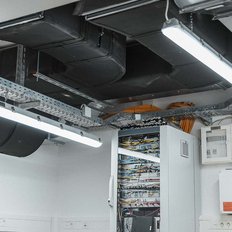Der Raum zeigt eine Vielzahl von Kabeln und Geräten, die ordentlich in einem Serverregal angeordnet sind, mit einer klaren Beleuchtung.