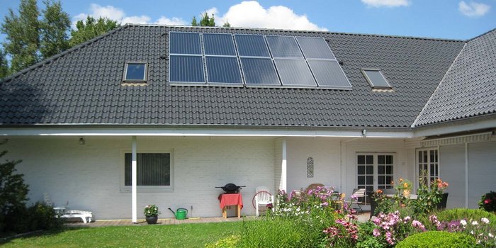 Ein modernes Haus mit einem schrägen Dach, das mit Solarpanelen ausgestattet ist, umweltfreundliche Energie erzeugend.