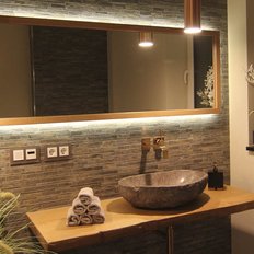 Ein elegantes Badezimmer mit einem großen, runden Waschbecken aus Stein und einem Holzregal, das mit Handtüchern dekoriert ist.