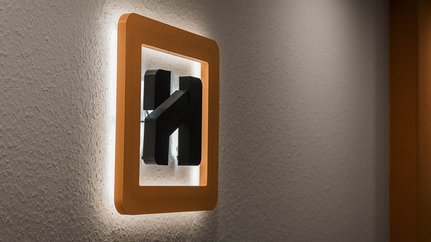 Ein modernes Lichtschalterdesign mit einem orangefarbenen Rahmen, der sanft an der Wand leuchtet und einen minimalistischen Stil zeigt.