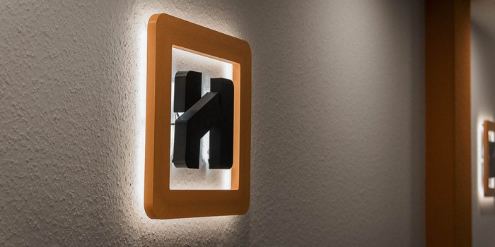 Ein modernes Lichtschalterdesign mit einem orangefarbenen Rahmen, der sanft an der Wand leuchtet und einen minimalistischen Stil zeigt.