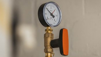 Ein Manometer zeigt einen Druck von etwa 3 bar an, montiert an einem goldenen Ventil mit einem orangefarbenen Griff.