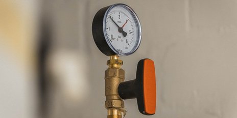 Ein Manometer zeigt einen Druck von etwa 3 bar an, montiert an einem goldenen Ventil mit einem orangefarbenen Griff.
