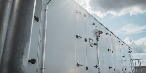 Ein moderner, weißer Container steht unter einem klaren Himmel, mit Wolken, die sanft vorbeiziehen.