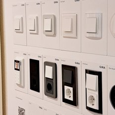 Eine Wand mit verschiedenen Lichtschaltern und Steckdosen in unterschiedlichen Designs und Farben, präsentiert in einem modernen Stil.