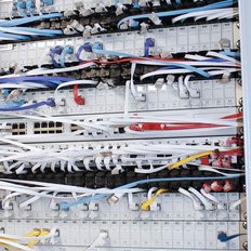 Ein Kabelmanagementsystem mit zahlreichen bunten Kabeln, die ordentlich in einem Schrank angeordnet sind.