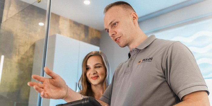 Die beiden Personen scheinen in ein Gespräch vertieft zu sein, während der Mann mit einer Hand auf das Tablet zeigt.