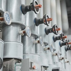 Eine Reihe von silbernen Rohren mit Druckmessgeräten und Ventilen, die in einer industriellen Umgebung installiert sind.